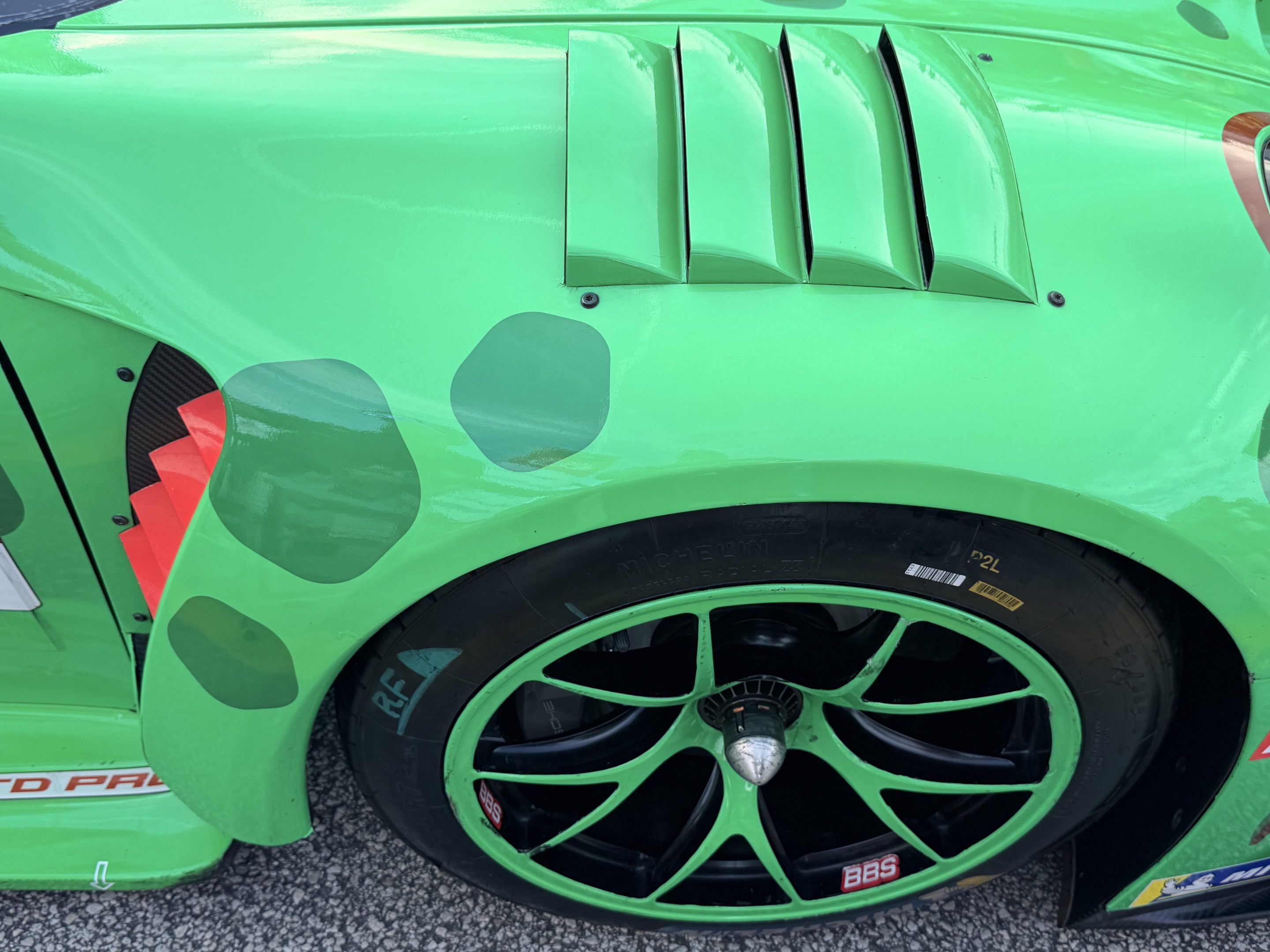 The right front wheel and fender of AO Racing’s Rexy dinosaur Porsche 911 GT3